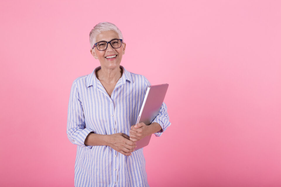 Studio portrait of a happy mature woman holding a laptop